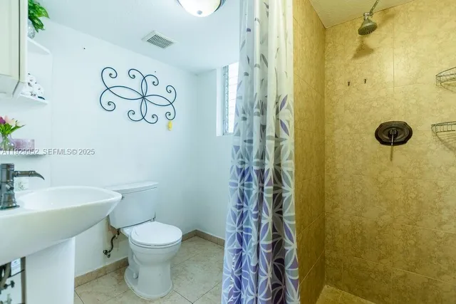 a bathroom with a toilet sink and shower curtain