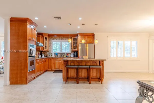 a kitchen with stainless steel appliances kitchen island granite countertop a refrigerator and a sink