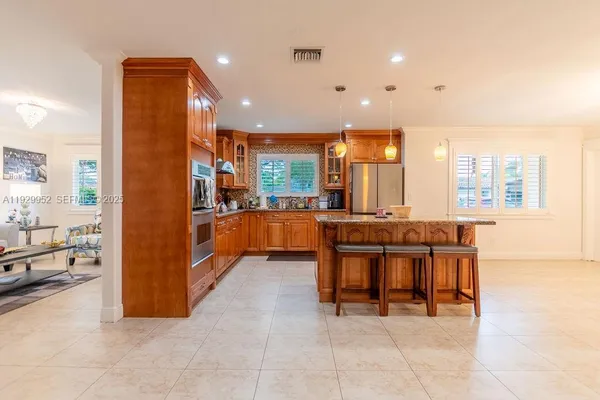 a large kitchen with stainless steel appliances kitchen island granite countertop a refrigerator and a sink