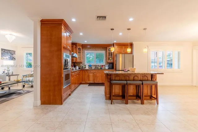 a large kitchen with stainless steel appliances kitchen island granite countertop a refrigerator and a sink