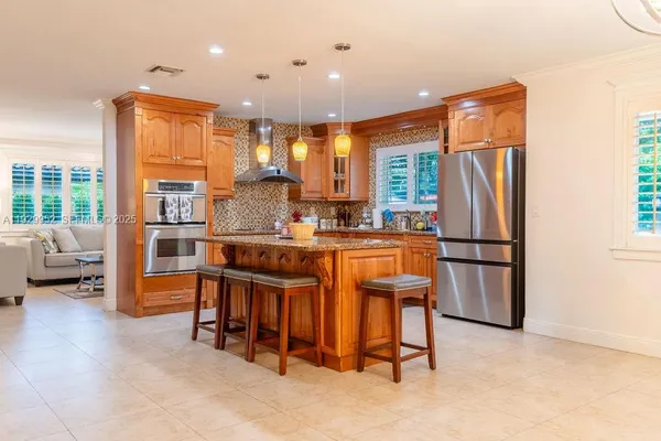 a open kitchen with stainless steel appliances granite countertop a refrigerator a stove a sink a dining table and chairs with wooden floor