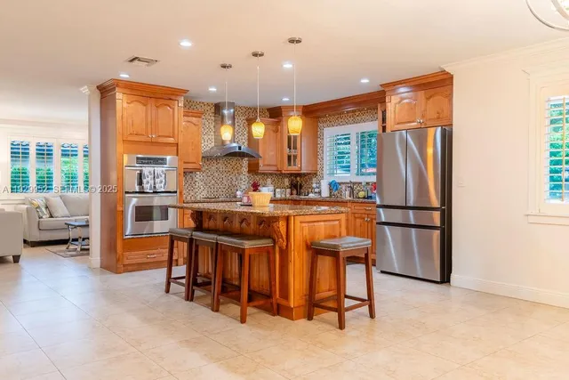 a open kitchen with stainless steel appliances granite countertop a refrigerator a stove a sink a dining table and chairs with wooden floor