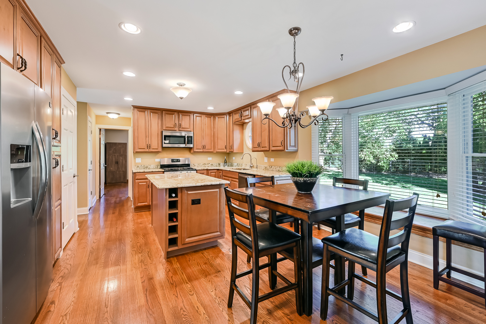 2 Carriage Lane Lemont, IL 60439 - Photo 9 of 44 a kitchen with stainless steel appliances granite countertop a stove top oven a refrigerator a sink and a dining table with wooden floor
