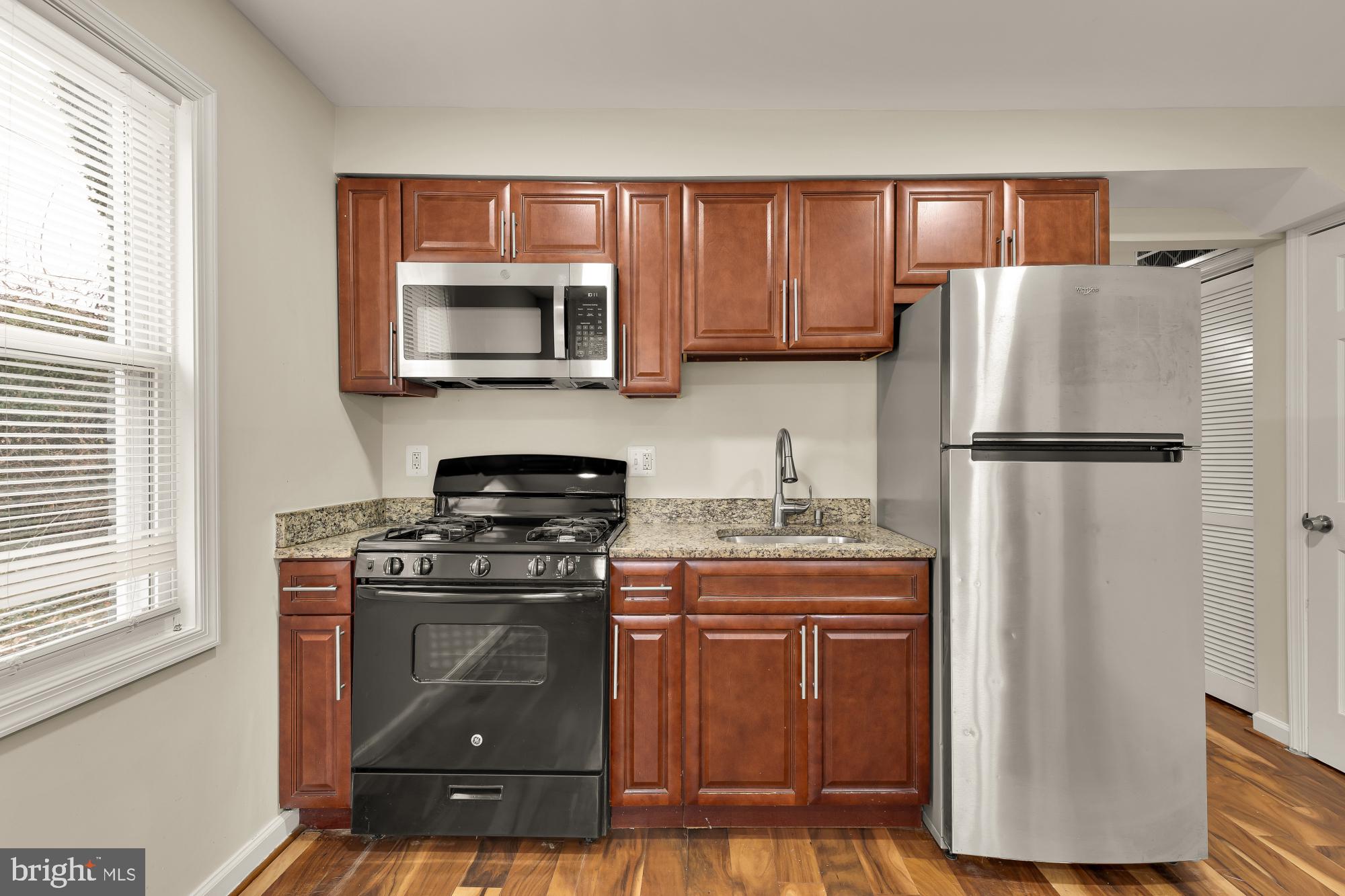 4131 Hunt Place Northeast, Unit A Washington, DC 20019 - Photo 3 of 9 a kitchen with granite countertop a stove top oven and refrigerator