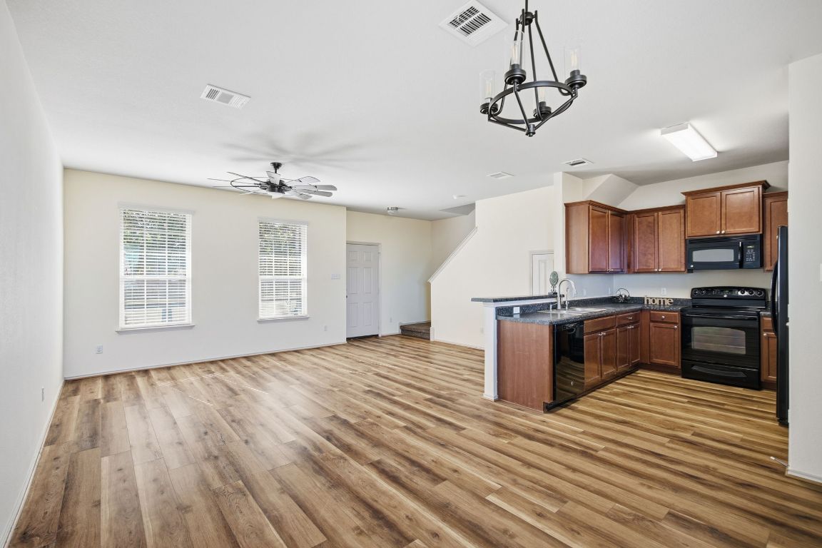 408 Azurite Drive Jarrell, TX 76537 - Photo 34 of 34 a kitchen with stainless steel appliances granite countertop a stove top oven a sink dishwasher a refrigerator and a dining table with wooden floor