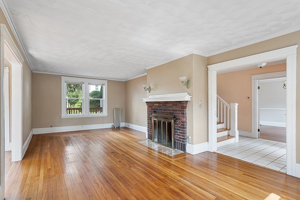 27 Woodman Road Worcester, MA 01602 - Photo 8 of 27 an empty room with wooden floor fireplace and windows
