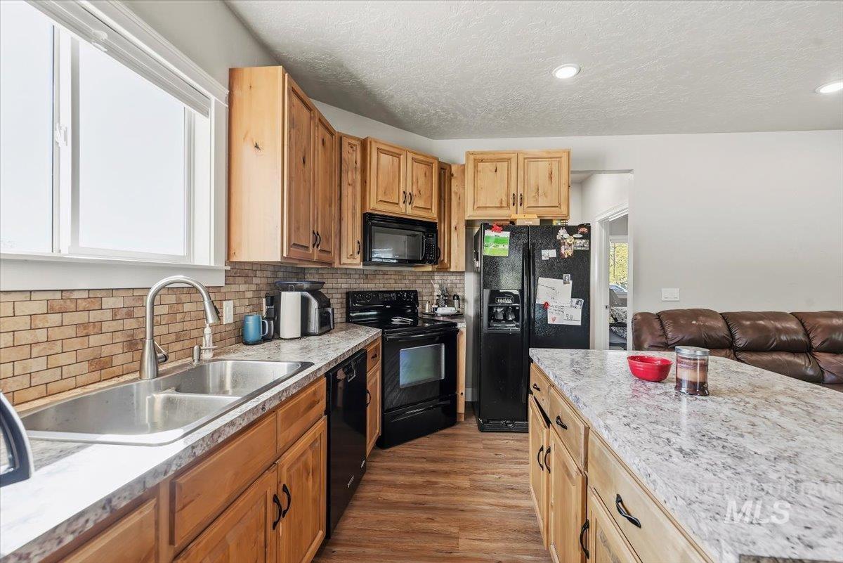24240 Tiger Lane Caldwell, ID 83607 - Photo 40 of 50 Kitchen featuring wood cabinetry, stainless steel double basin sink, black appliances, and a tiled backsplash