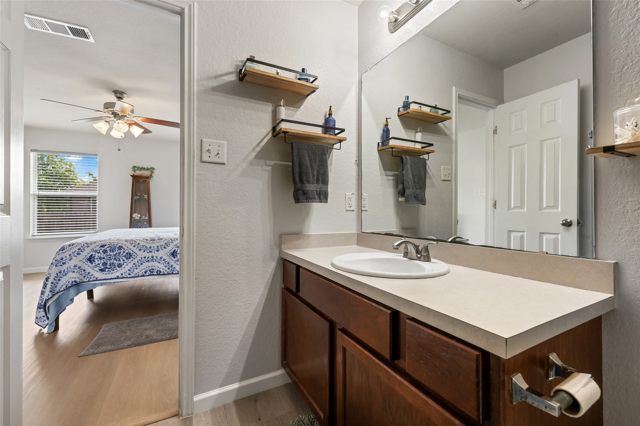 144 Calcite Lane Jarrell, TX 76537 - Photo 24 of 38 Functional bathroom vanity with ample counter space and a large mirror, adjacent to a bright bedroom.
