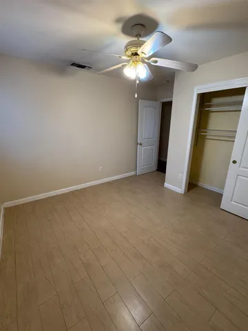 an empty room with closet and a chandelier fan