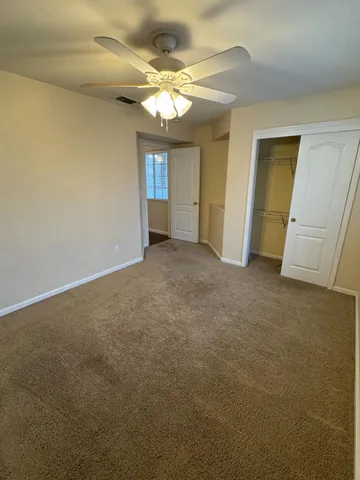 a view of an empty room with a chandelier fan