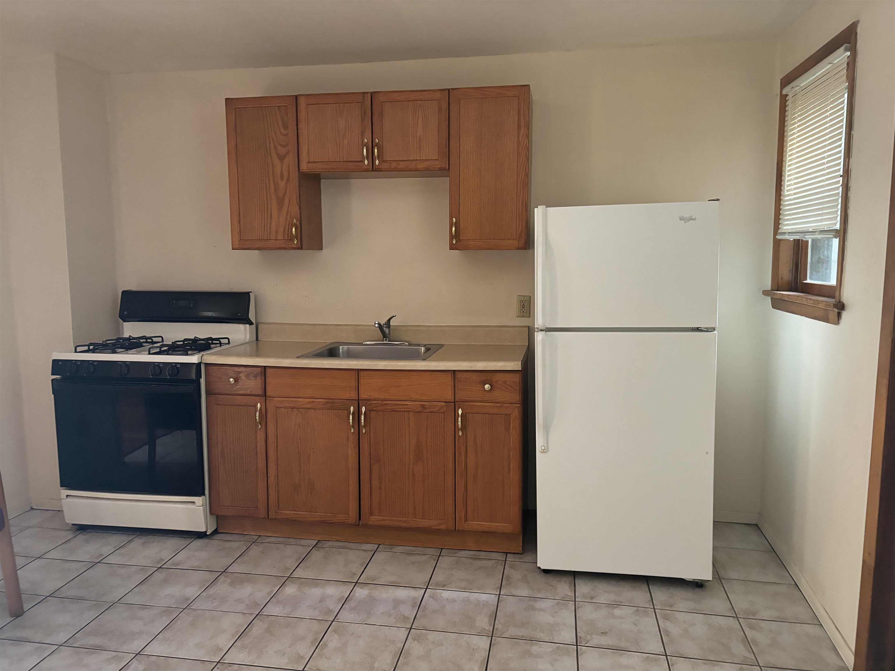 407 John F. Kennedy Boulevard, Unit 1 Bayonne, NJ 07002 - Photo 2 of 7 a kitchen with a refrigerator sink stove and cabinets