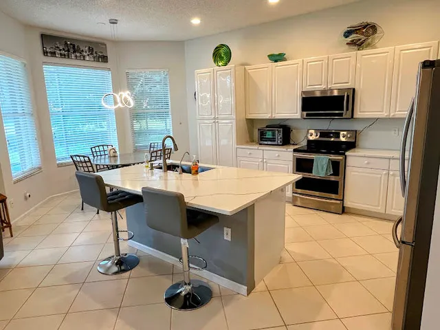 a kitchen with stainless steel appliances kitchen island granite countertop a sink and a refrigerator