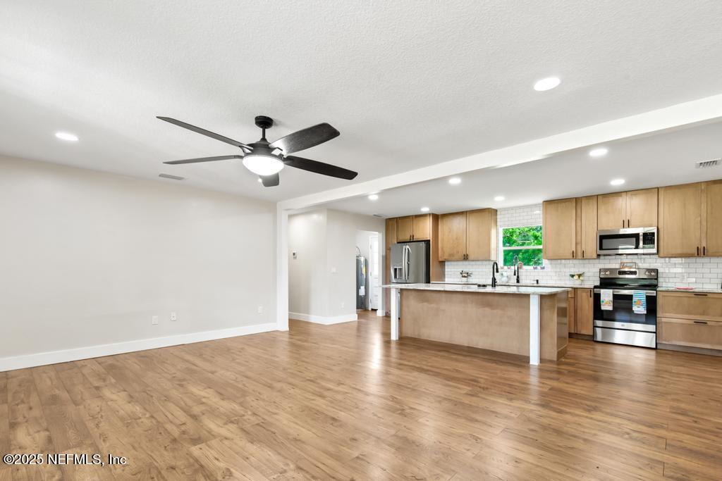 54308 Hurst Road Callahan, FL 32011 - Photo 12 of 49 a open kitchen with stainless steel appliances granite countertop a stove top oven a refrigerator a dining table and chairs with wooden floor
