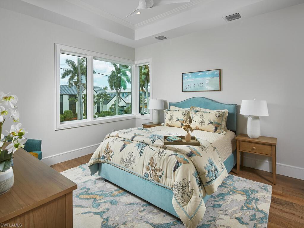 575 17th Avenue South Naples, FL 34102 - Photo 29 of 43 Bedroom with ceiling fan, a tray ceiling, and wood-type flooring