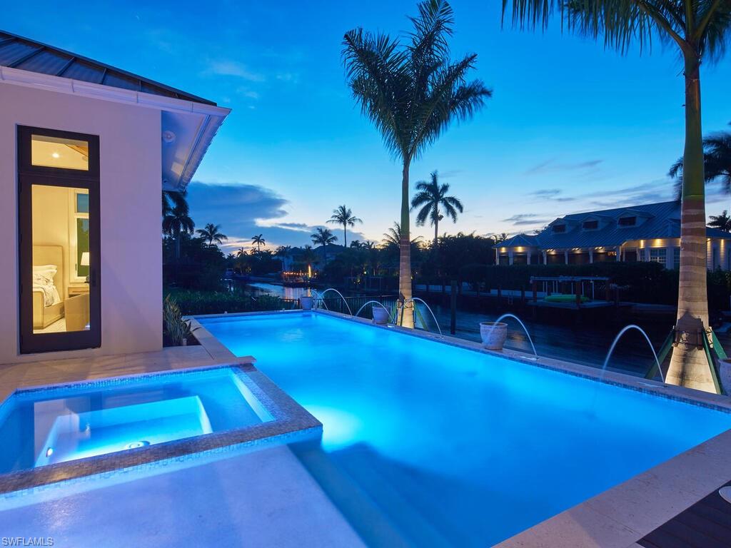 575 17th Avenue South Naples, FL 34102 - Photo 36 of 41 Pool at dusk featuring pool water feature and an in ground hot tub