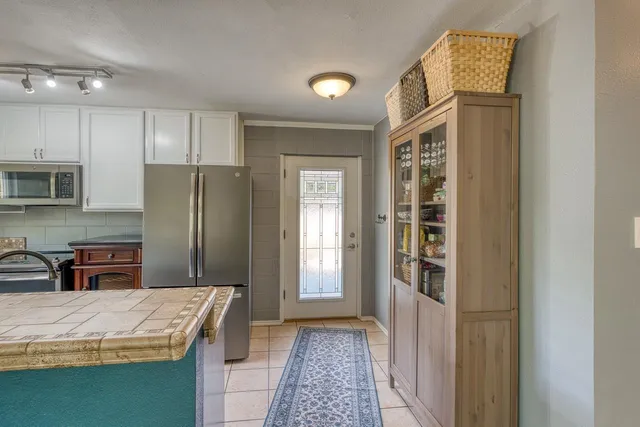 a bathroom with a granite countertop sink a refrigerator and a mirror