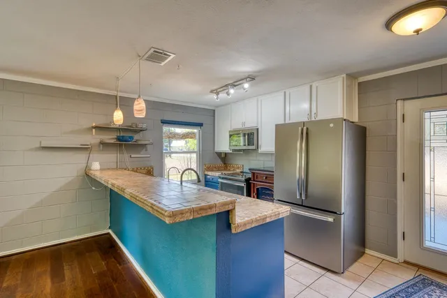 a kitchen with kitchen island a counter top space a sink refrigerator and cabinets