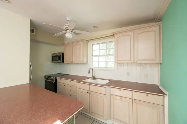 a kitchen with a sink dishwasher a stove and white cabinets with wooden floor