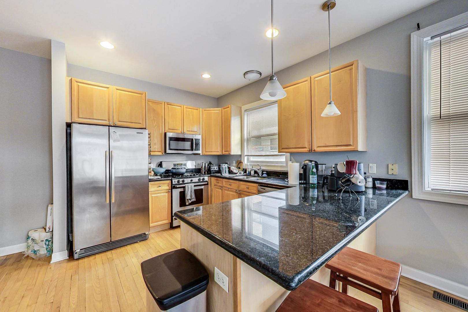 1330 West Fletcher Street, Unit 1 Chicago, IL 60657 - Photo 13 of 42 a kitchen with stainless steel appliances granite countertop a refrigerator a stove and white cabinets with wooden floor