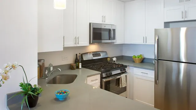 a kitchen with stainless steel appliances a stove a sink a refrigerator a microwave a counter space and cabinets