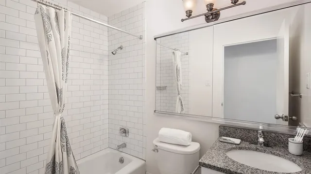 a bathroom with a granite countertop sink toilet a mirror a shower and a bathtub