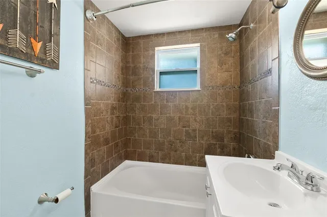 a bathroom with a sink and mirror with bathtub
