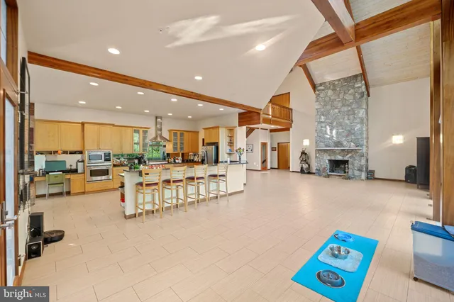 a dining hall with stainless steel appliances a dining table and chairs with the view of kitchen