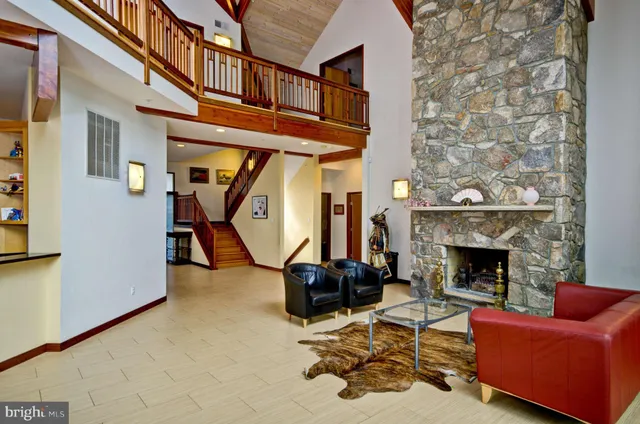 a living room with furniture a fireplace and floor to ceiling windows