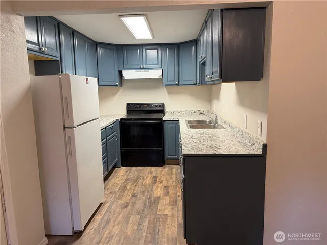 a kitchen with granite countertop stainless steel appliances a refrigerator a sink and a stove