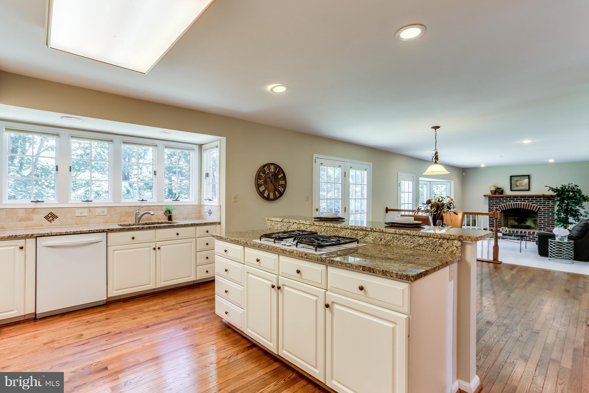 8258 Spring Branch Court Laurel, MD 20723 - Photo 10 of 26 a kitchen with granite countertop a stove a sink a refrigerator and white cabinets with wooden floor