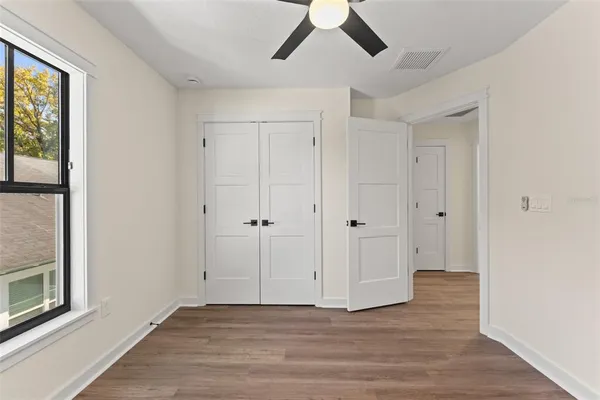 a view of an empty room with window and wooden floor