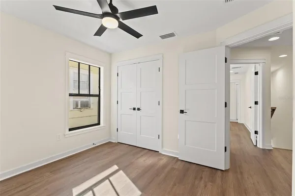 a view of empty room with wooden floor and fan