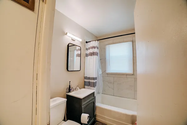 a bathroom with a granite countertop sink a toilet a mirror and shower
