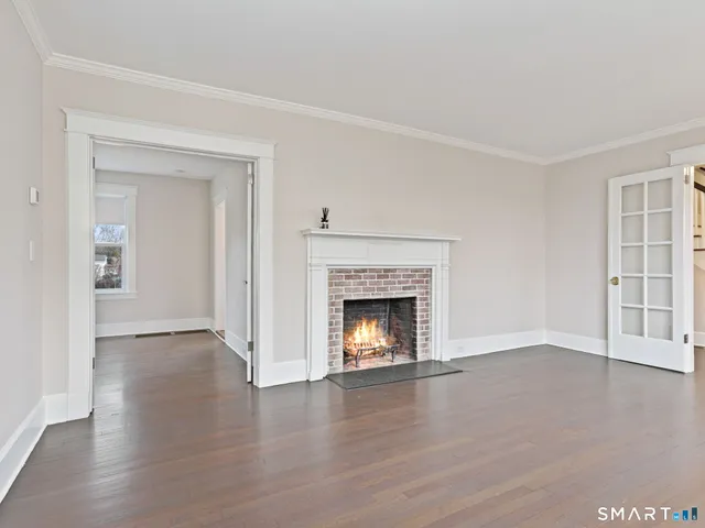 an empty room with wooden floor fireplace and windows