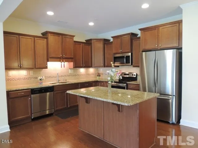a kitchen with granite countertop a refrigerator a sink a stove a microwave and cabinets