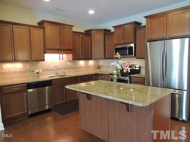 a kitchen with stainless steel appliances granite countertop a refrigerator a sink and a stove