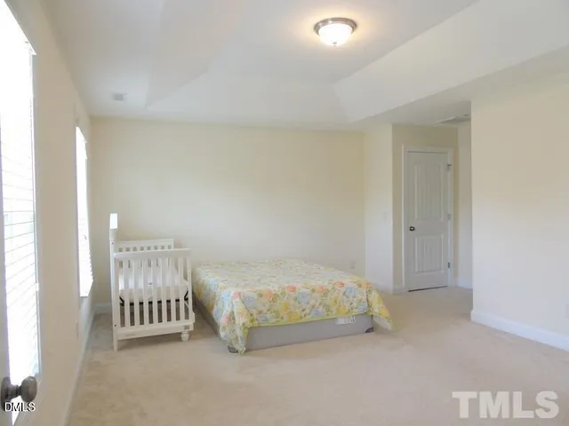 a spacious bedroom with a bed and a lamp