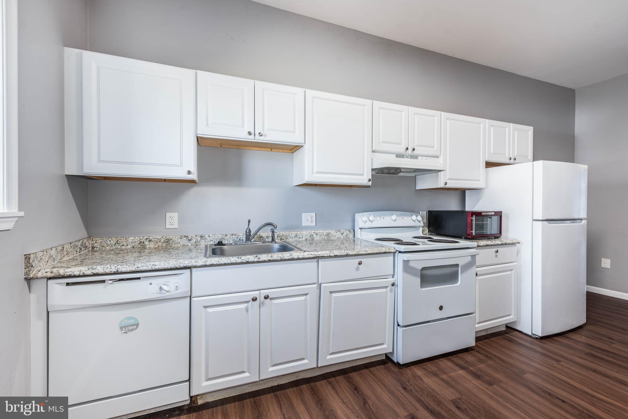2118 East Hoffman Street Baltimore, MD 21213 - Photo 6 of 19 a kitchen with stainless steel appliances granite countertop white cabinets sink and dishwasher
