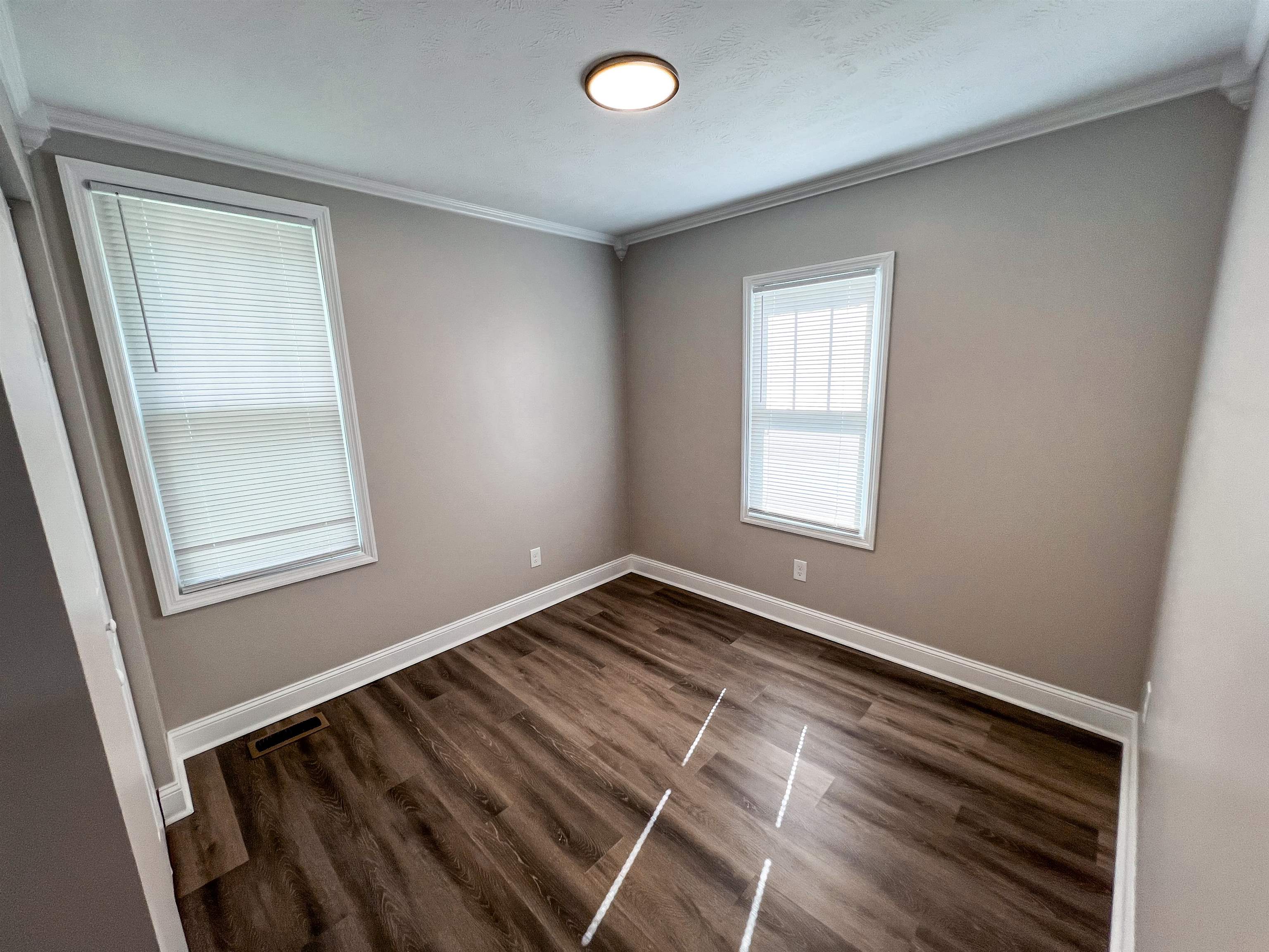 202 Morris Street Waynesboro, TN 38485 - Photo 12 of 36 Empty room with crown molding and dark wood-style flooring