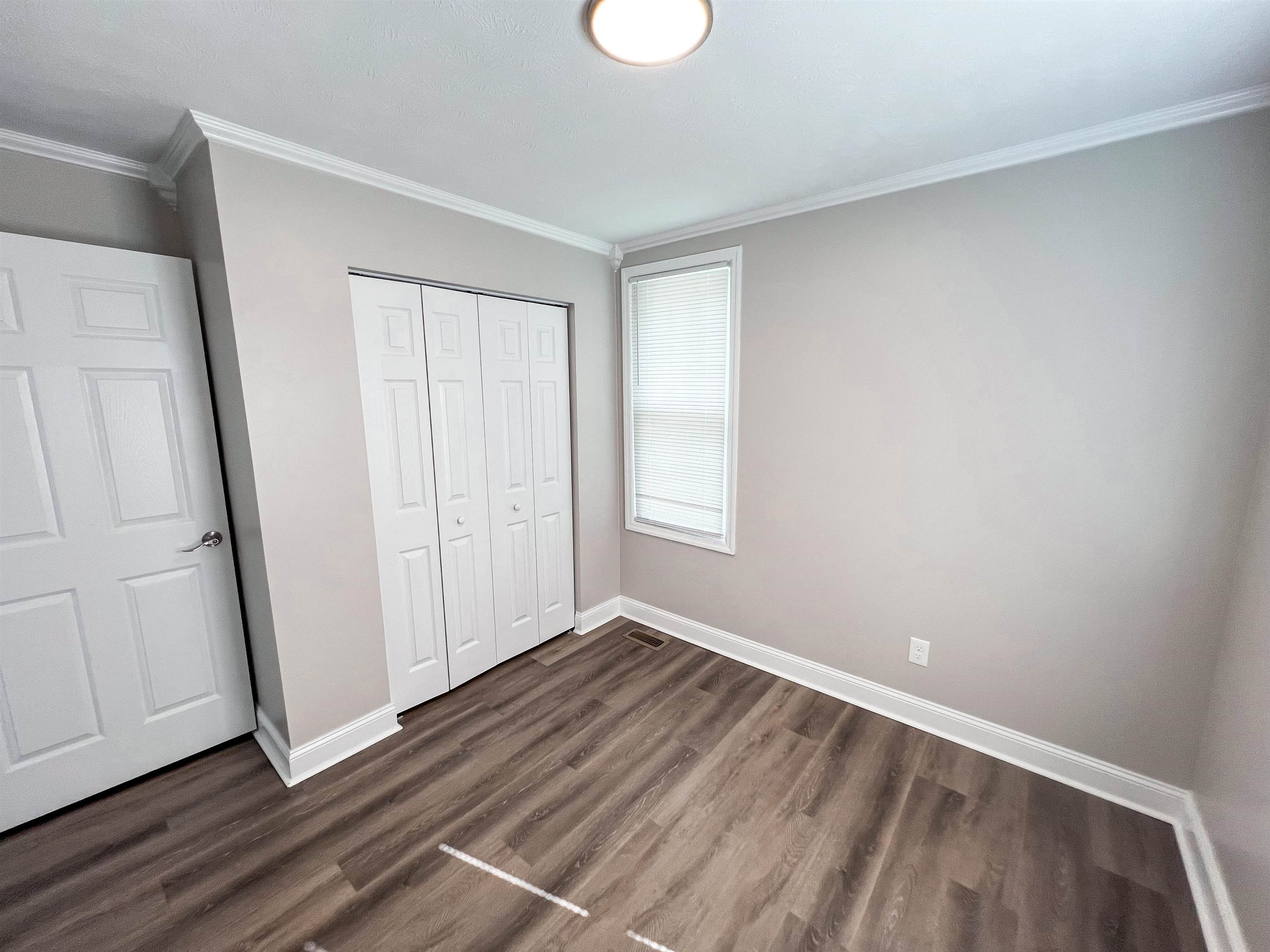 202 Morris Street Waynesboro, TN 38485 - Photo 13 of 36 Unfurnished bedroom with ornamental molding, a closet, and dark wood-type flooring