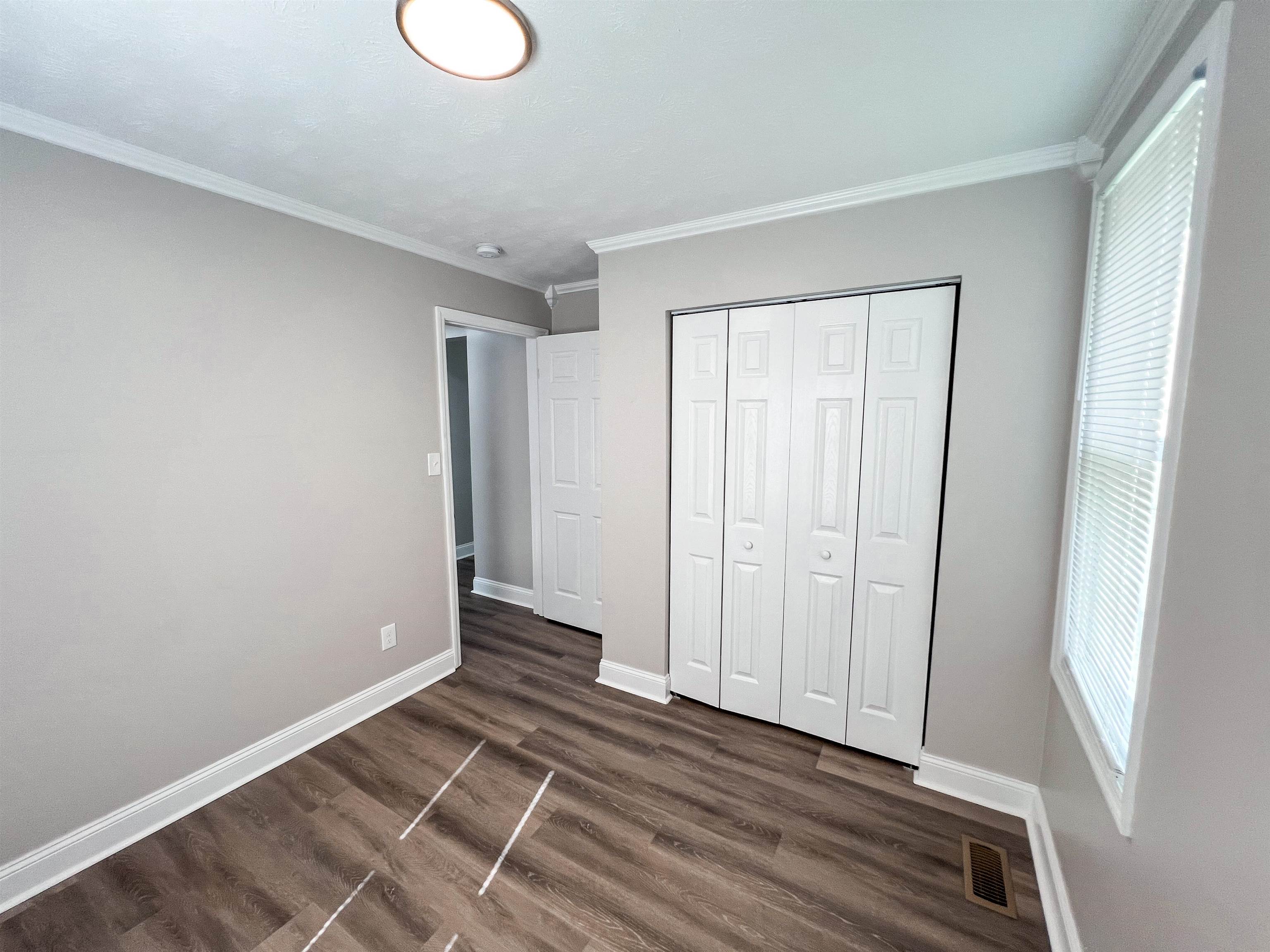 202 Morris Street Waynesboro, TN 38485 - Photo 14 of 36 Unfurnished bedroom with crown molding, dark wood finished floors, and a closet