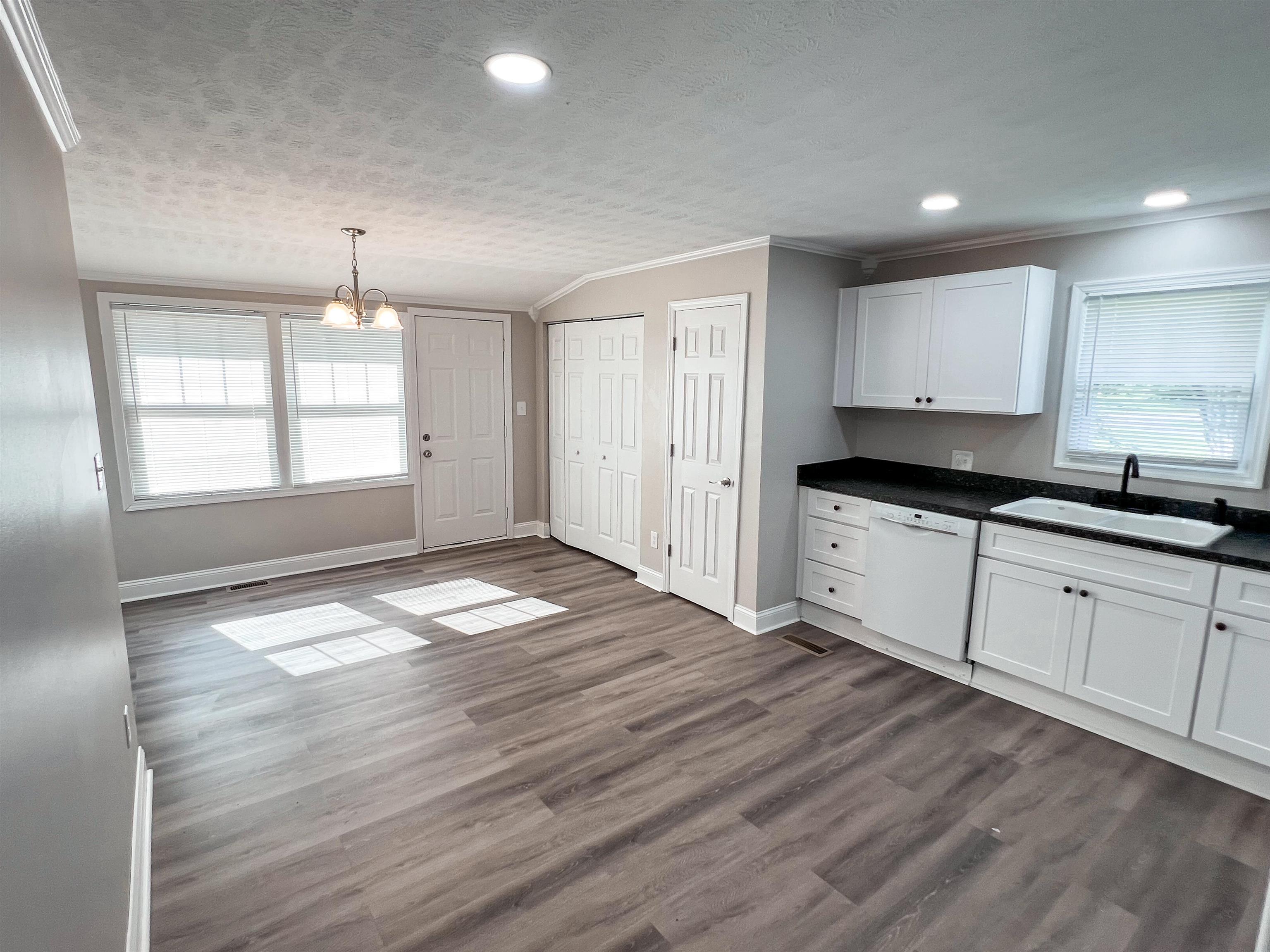 202 Morris Street Waynesboro, TN 38485 - Photo 17 of 36 Kitchen featuring healthy amount of natural light, ornamental molding, dark countertops, white dishwasher, and a chandelier