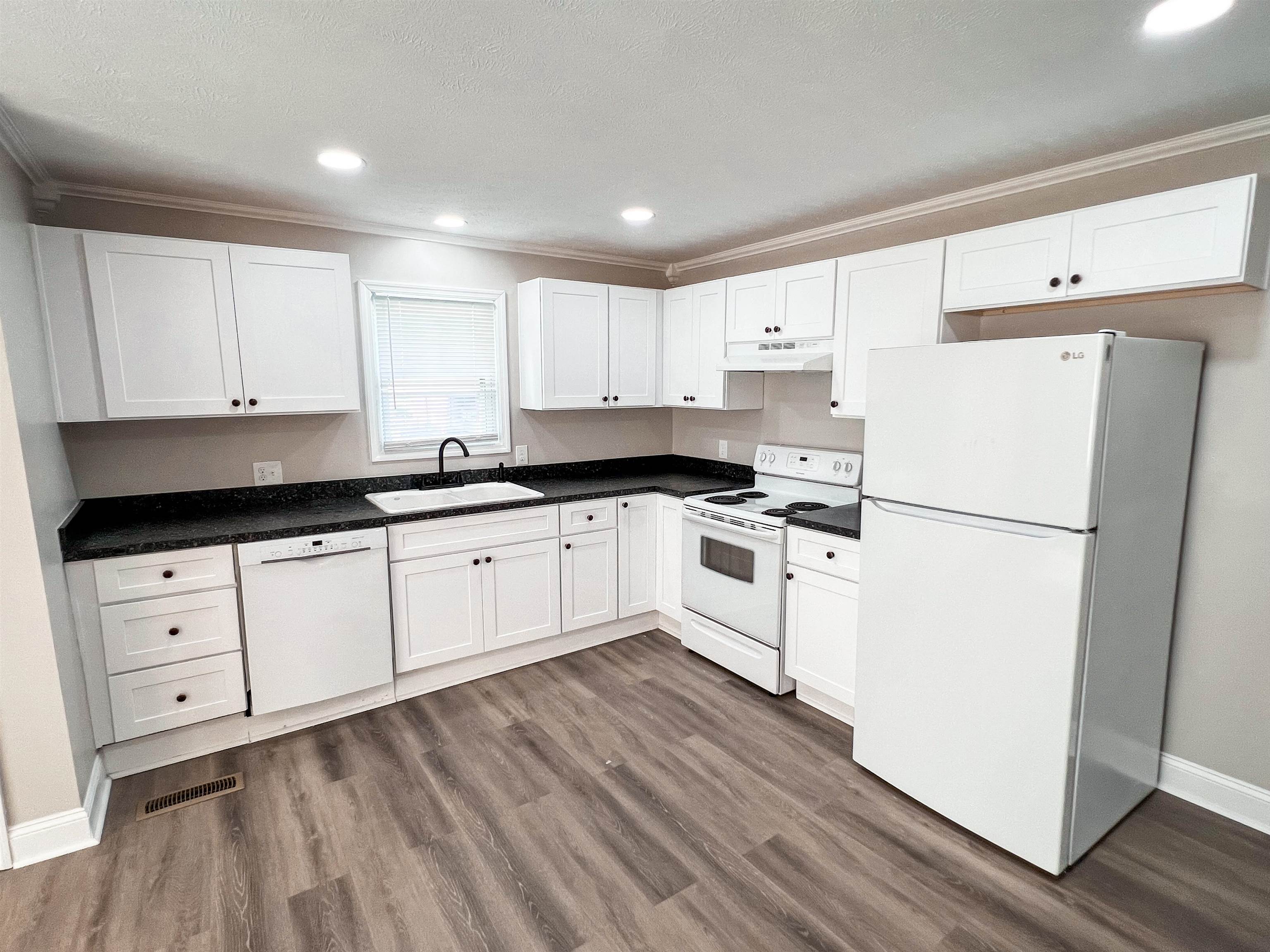 202 Morris Street Waynesboro, TN 38485 - Photo 19 of 36 Kitchen featuring white appliances, ornamental molding, white cabinets, dark wood-style floors, and recessed lighting