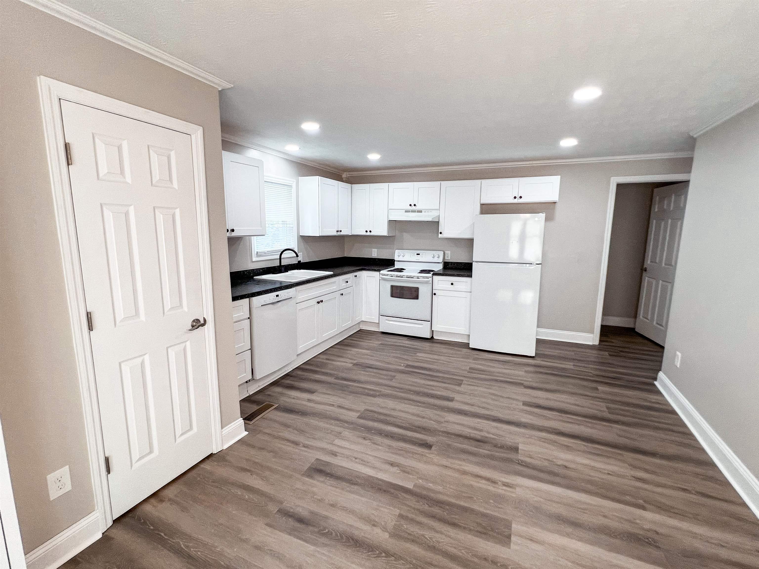 202 Morris Street Waynesboro, TN 38485 - Photo 22 of 36 Kitchen with white appliances, dark wood-style floors, crown molding, white cabinets, and dark countertops