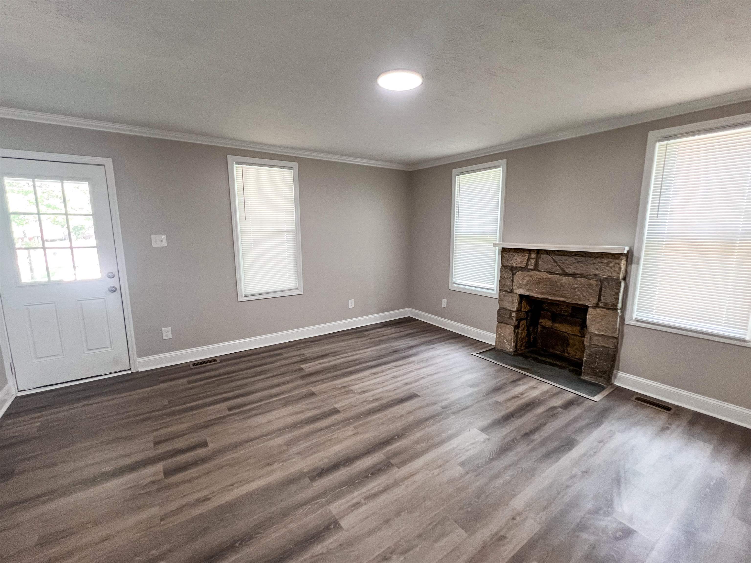 202 Morris Street Waynesboro, TN 38485 - Photo 3 of 36 Unfurnished living room featuring ornamental molding, a stone fireplace, dark wood-type flooring, and a textured ceiling