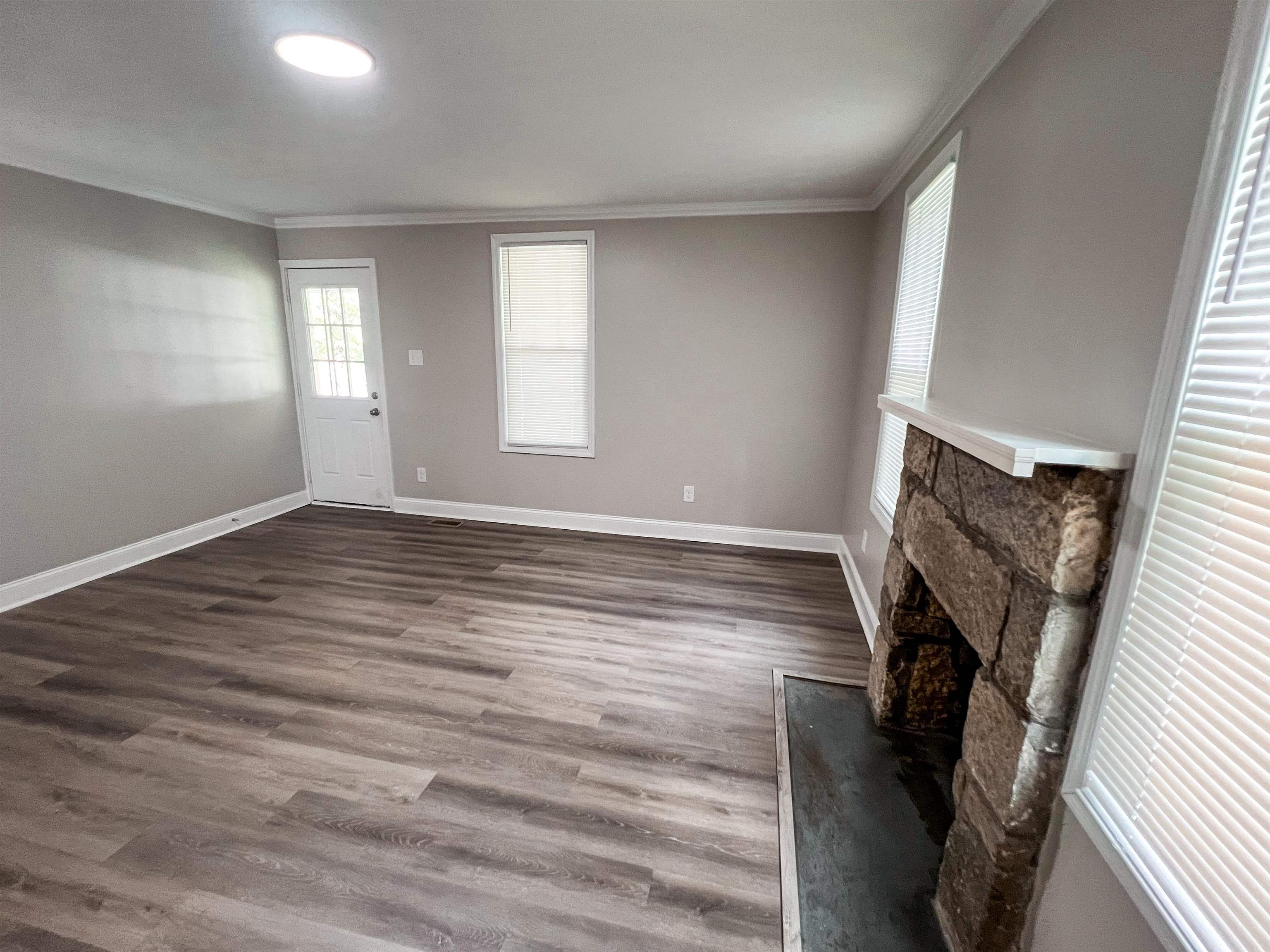 202 Morris Street Waynesboro, TN 38485 - Photo 5 of 36 Unfurnished living room with a fireplace, crown molding, and dark wood finished floors