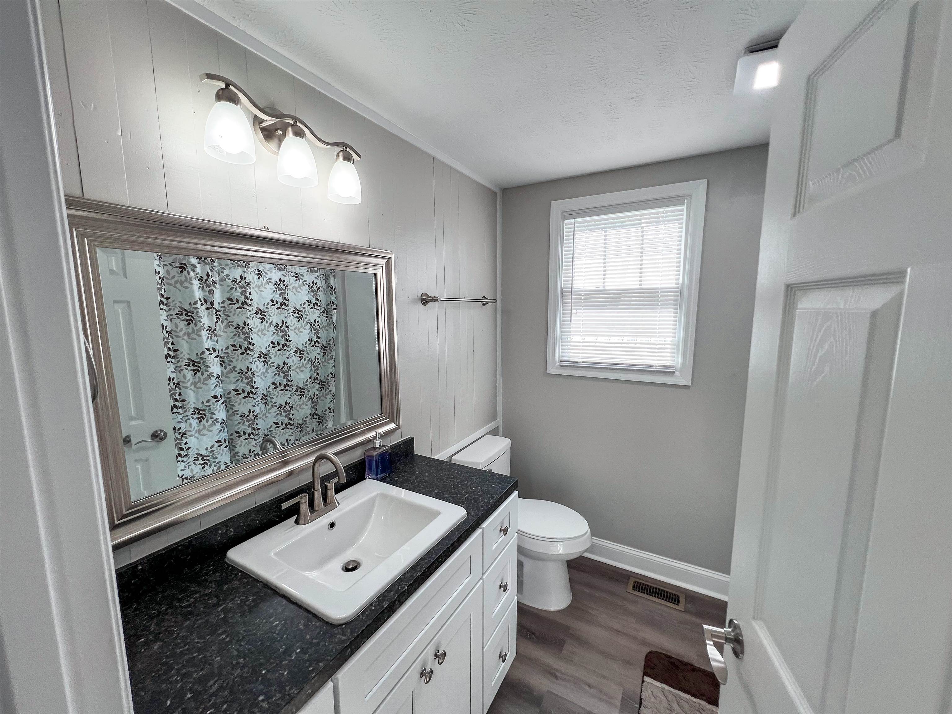202 Morris Street Waynesboro, TN 38485 - Photo 7 of 36 Bathroom featuring wood finished floors, vanity, a textured ceiling, and a shower