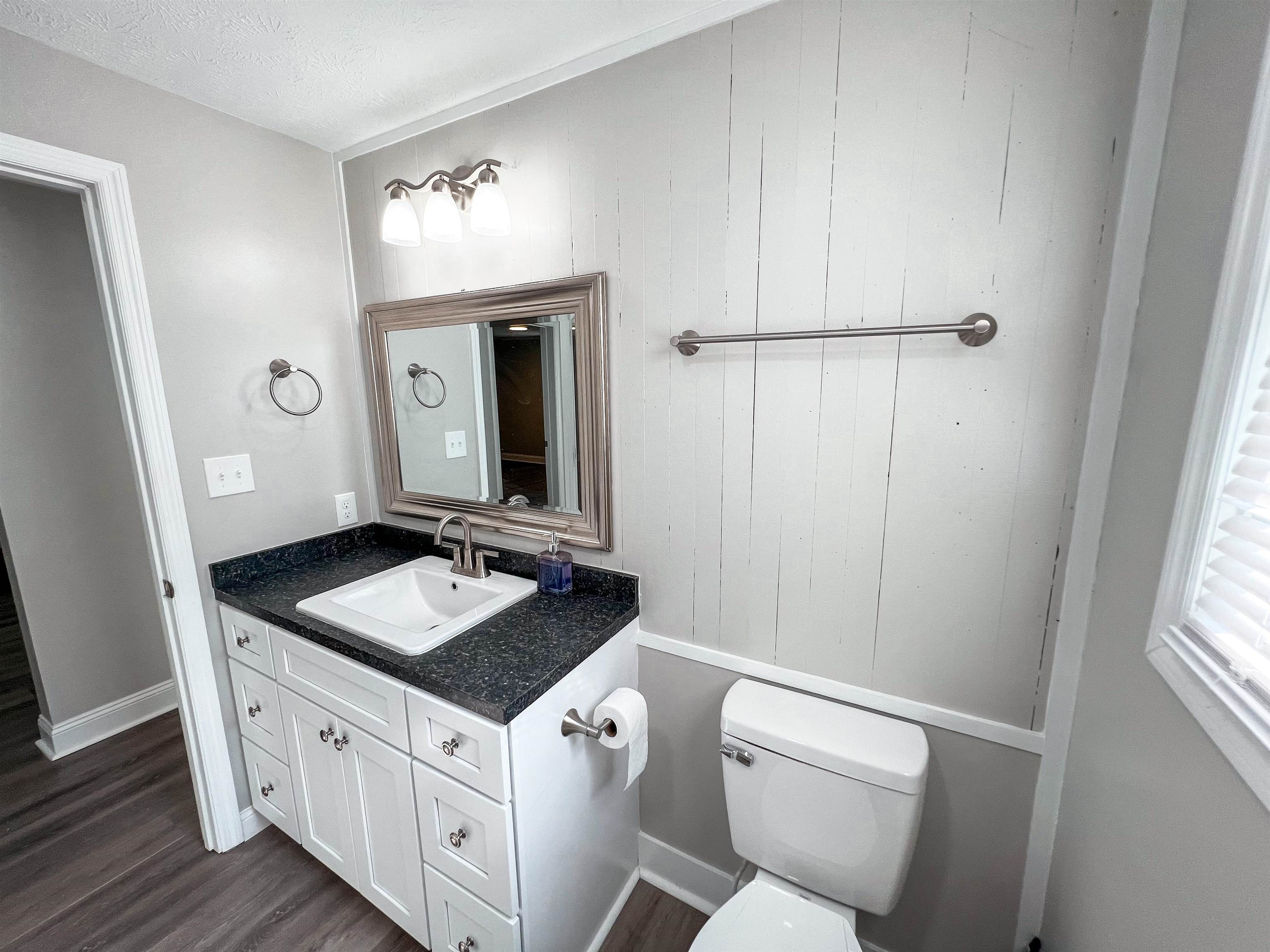202 Morris Street Waynesboro, TN 38485 - Photo 8 of 36 Half bath with vanity, wood finished floors, wooden walls, and a textured ceiling