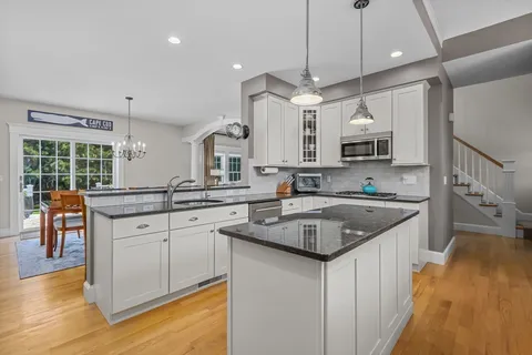 a kitchen with stainless steel appliances granite countertop a sink a stove and a wooden floors