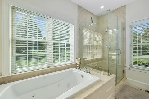a bathroom with a large tub a shower and view